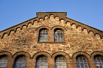 Historisches Fabrikgebäude mit Bruchsteinfassade und Bogenfenstern. Bild mit Textfreiraum