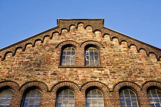 Historisches Fabrikgeb&auml;ude mit Bruchsteinfassade und Bogenfenstern. Bild mit Textfreiraum