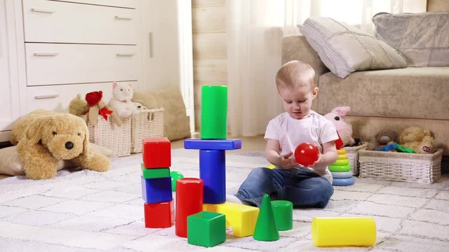 Little Caucasian child boy playing with colorful construction blocks
