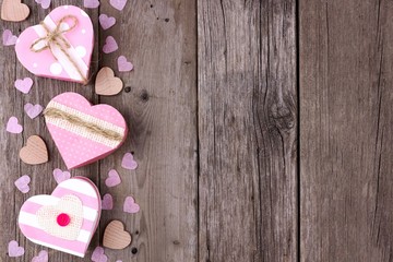 Valentines Day side border of heart shaped gift boxes with soft pink and burlap trim over wood