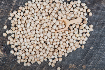 Chick peas on old wooden board with a wooden scoop