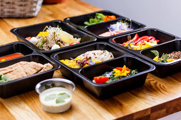 Healthy food and diet concept, restaurant dish delivery. Take away of fitness meal. Weight loss nutrition in foil boxes. Steamed veal with cous and vegetables at wood