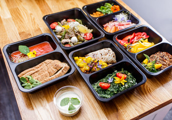 Healthy food and diet concept, restaurant dish delivery. Take away of fitness meal. Weight loss nutrition in foil boxes. Steamed veal with cous and vegetables at wood