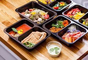 Healthy food and diet concept, restaurant dish delivery. Take away of fitness meal. Weight loss nutrition in foil boxes. Steamed veal with cous and vegetables at wood
