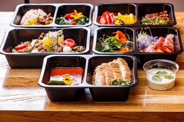 Healthy food and diet concept, restaurant dish delivery. Take away of fitness meal. Weight loss nutrition in foil boxes. Steamed veal with cous and vegetables at wood