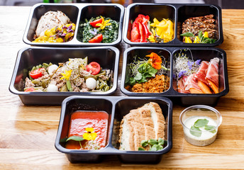 Healthy food and diet concept, restaurant dish delivery. Take away of fitness meal. Weight loss nutrition in foil boxes. Steamed veal with cous and vegetables at wood