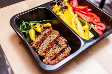 Healthy food and diet concept, restaurant dish delivery. Take away of fitness meal. Weight loss nutrition in foil boxes. Steamed veal with cous and vegetables at wood