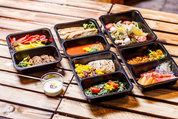 Healthy food and diet concept, restaurant dish delivery. Take away of fitness meal. Weight loss nutrition in foil boxes. Steamed veal with cous and vegetables at wood