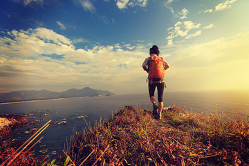successful hiker walking on seaside mountain peak