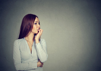 Preoccupied anxious young woman biting fingernails