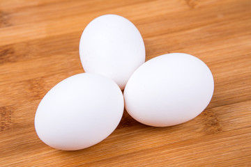 Whole white eggs isolated on a wood background