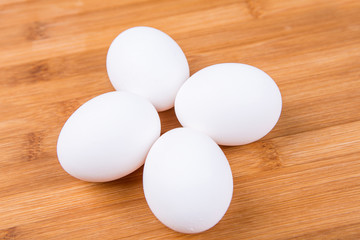 Whole white eggs isolated on a wood background