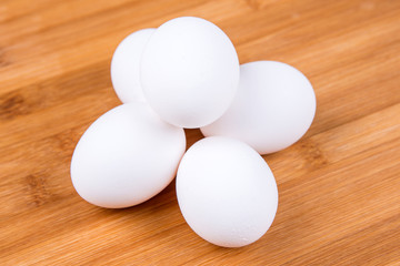 Whole white eggs isolated on a wood background