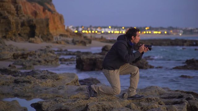 A photographer taking photos in the sea at sunset