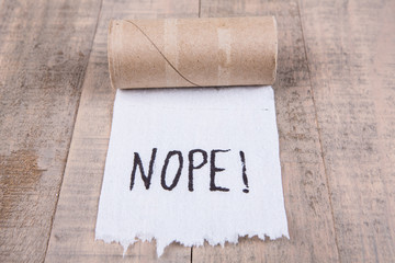 Toilet paper rolls out of paper with message isolated on a wood background