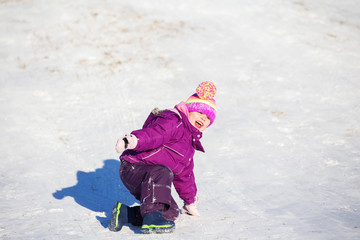 Four year old happy girl sliding downhill on a crazy carpet on a winter hill