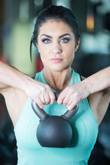 Healthy woman with piercing blue eyes holding weight ball in gym