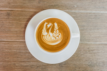 Close up white cup of Coffee, latte with beautiful latte art on the wooden table.