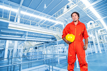Fototapeta premium Asian engineers holding a yellow hardhat on Factory equipment i