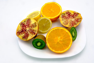 Sections of orange, lemon, kiwi and Pomegrenade  fruits in a pla