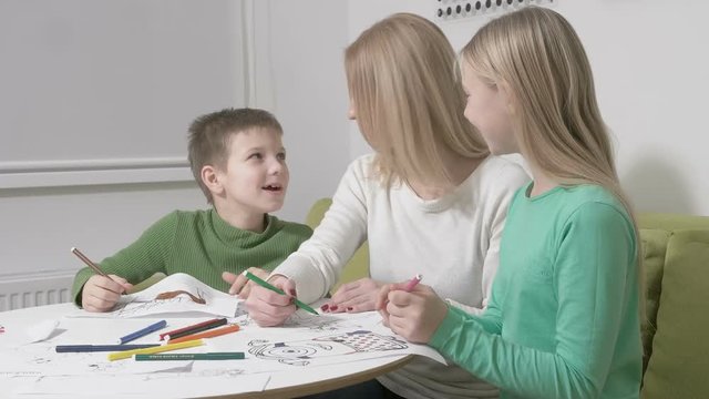 Happy family or Mother with cute children drawing with colorful pencils