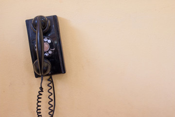 Black antique vintage analog telephone dialing or scrolling phone on old wall. Contact us concept.