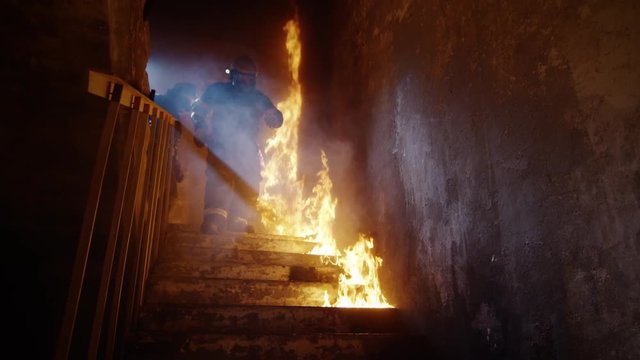 Fully Equipped Firefighters Coming Down on Burning Stairs. Building is On Fire. Shot in Slow Motion.  Shot on RED EPIC (uhd).