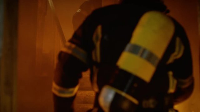Two Brave Firefighters Enter Into Open Doors and Run Up The Burning Stairs. Building is on Fire. Smoke and Open Flames Everywhere. In Slow Motion. Shot on RED EPIC (uhd).