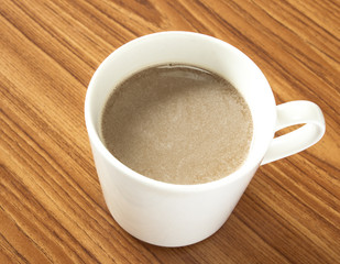 Closeup shot of coffee with cream in porcelain cup.