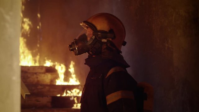 Portrait of a Brave Firefighter Inspecting Burning Building. He's Flashlight is Switched on and He Looks Into the Camera. Slow Motion.  Shot on RED EPIC (uhd).