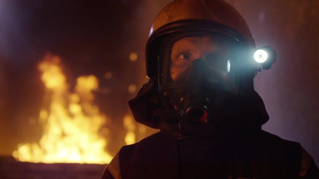 Building is on Fire. Brave Fireman Turns Around and Looks Into the Camera. Tongues of Flame are Licking Walls of the House.  Shot on RED EPIC (uhd).