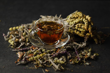 Transpatent cup of herbal tea with dried herbs