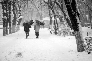 Snowing urban landscape with people passing by
