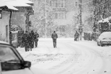 Snowing urban landscape with people passing by
