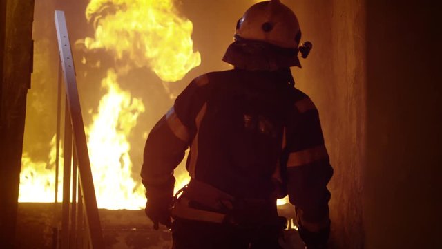 Building is On Fire. Fireman Looks up and Starts Going Upstairs. Open Flames are Seen on Stairs.  Shot on RED EPIC (uhd).