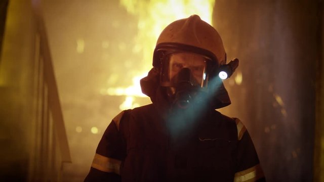 Portrait of a Brave Firefighter Standing in a Burning Building. Raging Fire Flares Up in the Background.  Shot on RED EPIC (uhd).