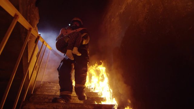 Brave Fireman Descends Burning Stairs with Saved Little Girl in His Hands. Open Flames are Seen Everywhere.  Shot on RED EPIC (uhd).