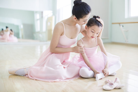 Young ballet instructor and little girl in ballet studio