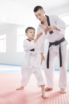 Young instructor teaching boy Tae Kwon Do
