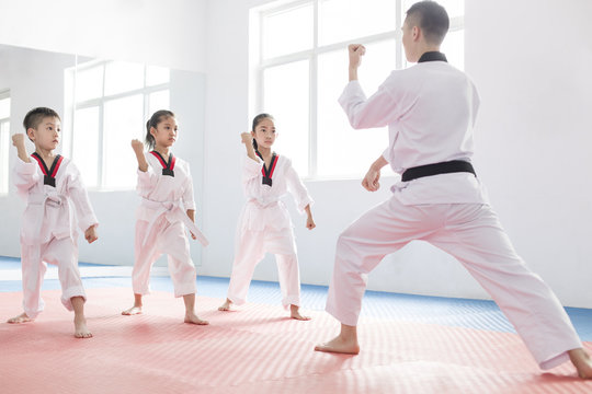 Young instructor teaching children Tae Kwon Do