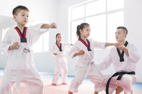Young instructor teaching children Tae Kwon Do