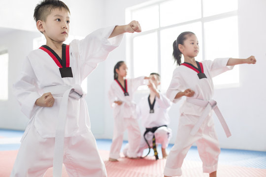 Young instructor teaching children taekwondo in studio