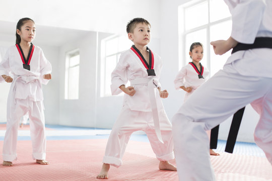 Young instructor teaching children Tae Kwon Do