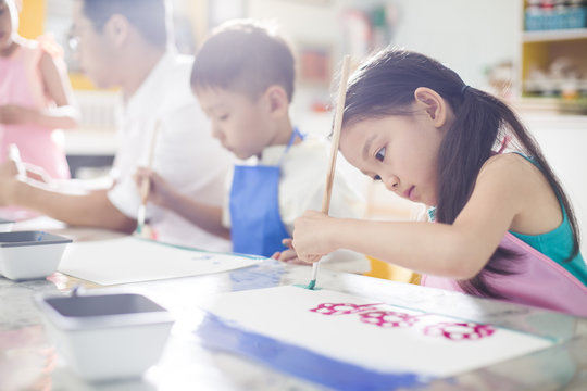 Little children painting in art class with teacher
