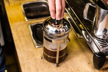 Barista presses ground coffee using tamper.