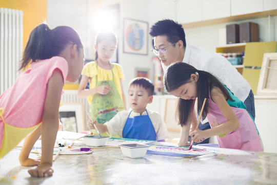 Children painting in the art class with teacher