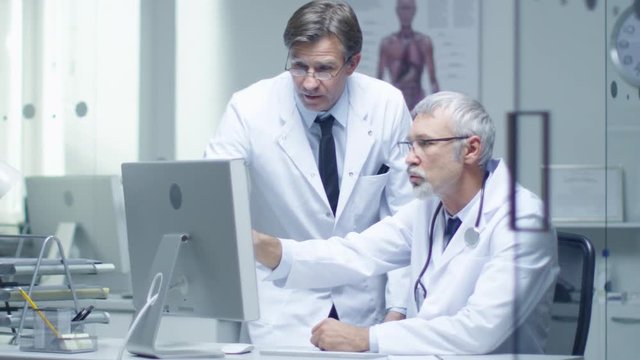 Senior Doctor and His Assistant Discuss Patient's Log on Personal Computer. In Slow Motion.  Shot on RED Cinema Camera in 4K (UHD).