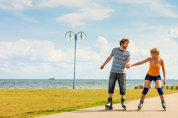 Fototapeta premium Young couple on roller skates riding outdoors
