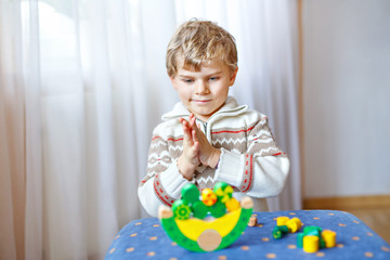 Kid boy playing with wooden balance toy at home