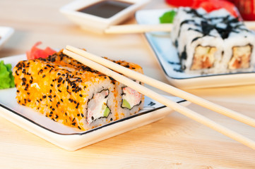 Sushi rolls on the white plate on wooden background